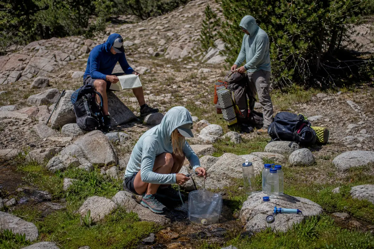 Backpackers stopping at the last reliable source to fill capacity, separate untreated water, and prepare a treatment backup - backpacking water mistakes | KnowOutdoor