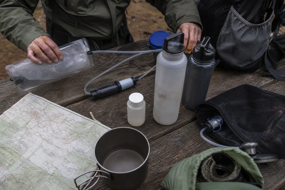 Backpacking water containers, filter, chemical backup, and separate clean and untreated sides arranged beside a route map - backpacking water system | KnowOutdoor