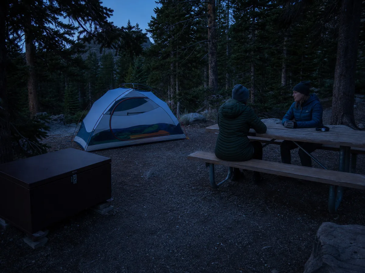 Simple settled first campsite with pitched tent secured food headlamps and a quiet evening at a generic frontcountry site - beginner camping night | KnowOutdoor