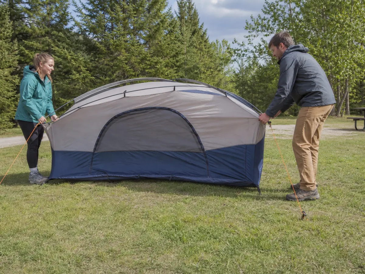Two campers raising a tent low from an anchored windward end in steady wind - controlled wind pitching sequence | KnowOutdoor