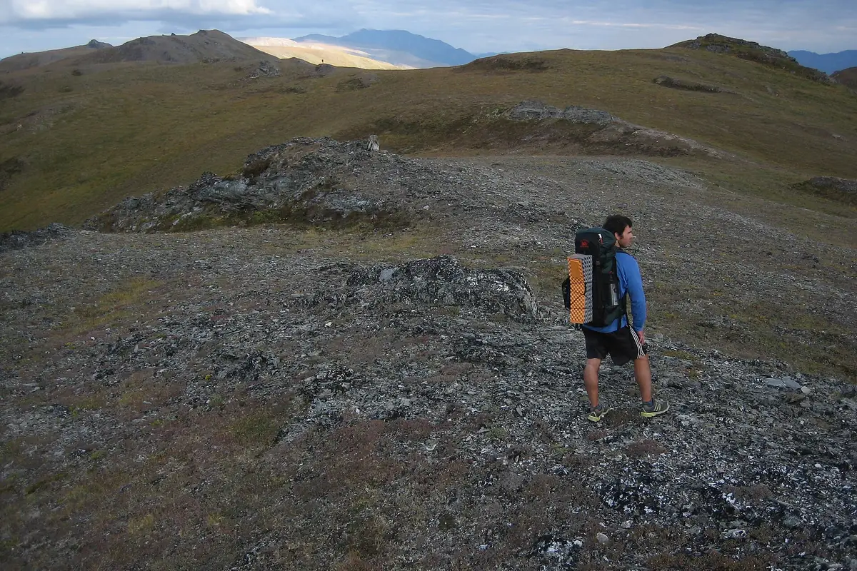 Hiker crossing open tundra below the Alaska Range - Alaska Range | KnowOutdoor