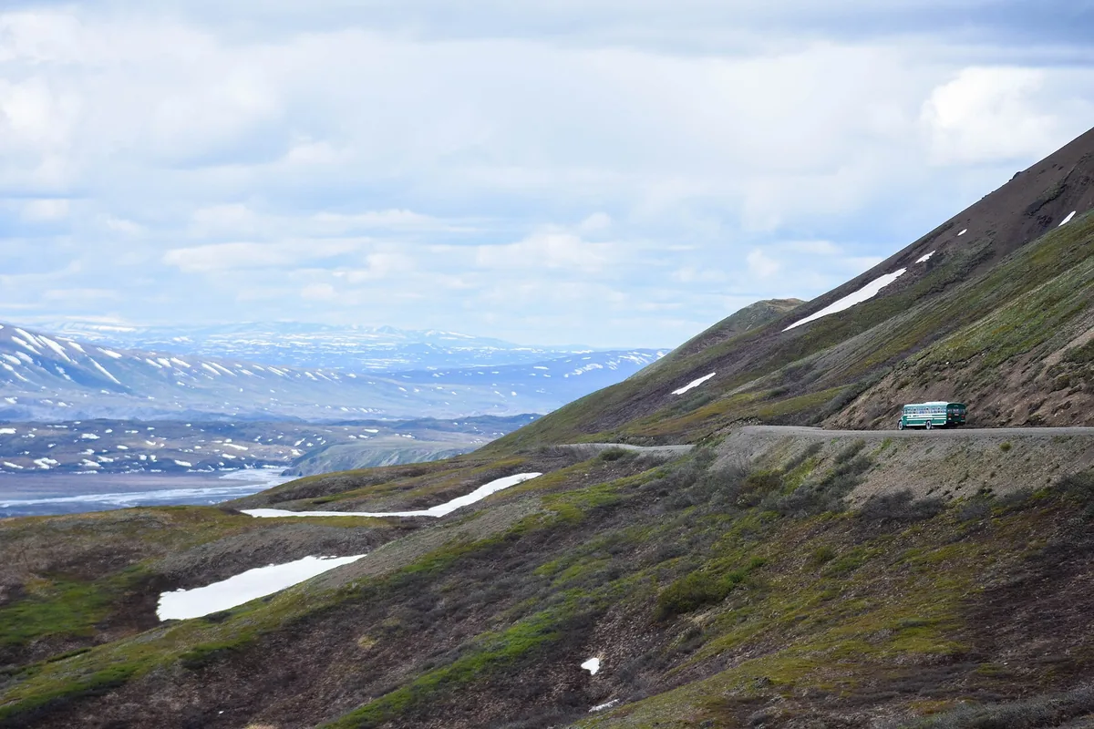 Denali Park Road crossing tundra below mountain slopes - Alaska Range | KnowOutdoor