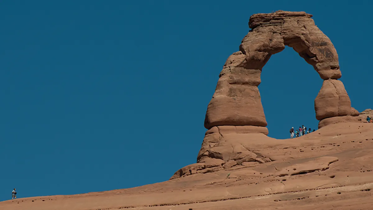 People standing beneath Delicate Arch for scale at Arches National Park