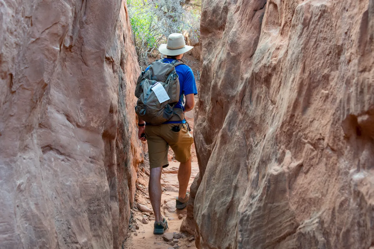 Hiker walking through a narrow sandstone passage in Fiery Furnace at Arches National Park
