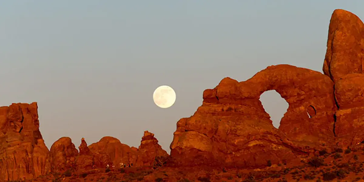 Moon rising behind sandstone formations at Arches National Park
