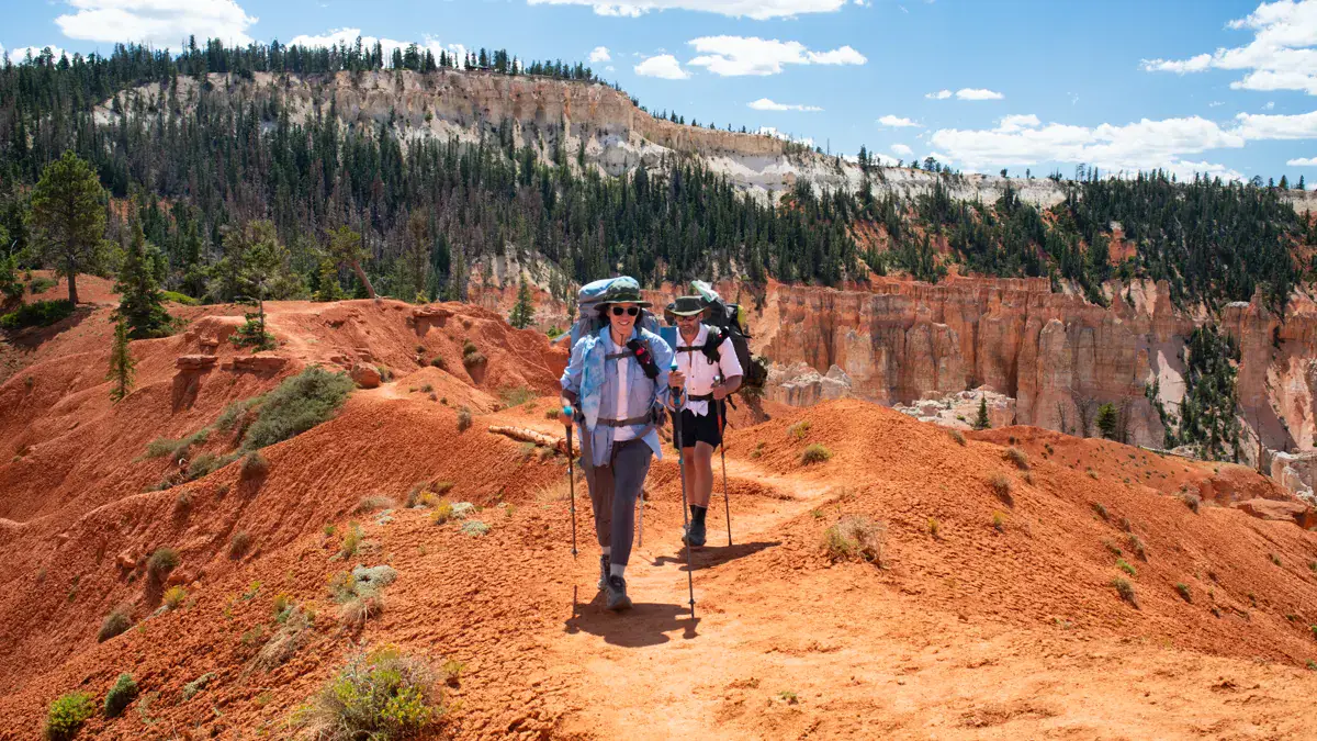 Two backpackers walking through red rock backcountry at Bryce Canyon National Park