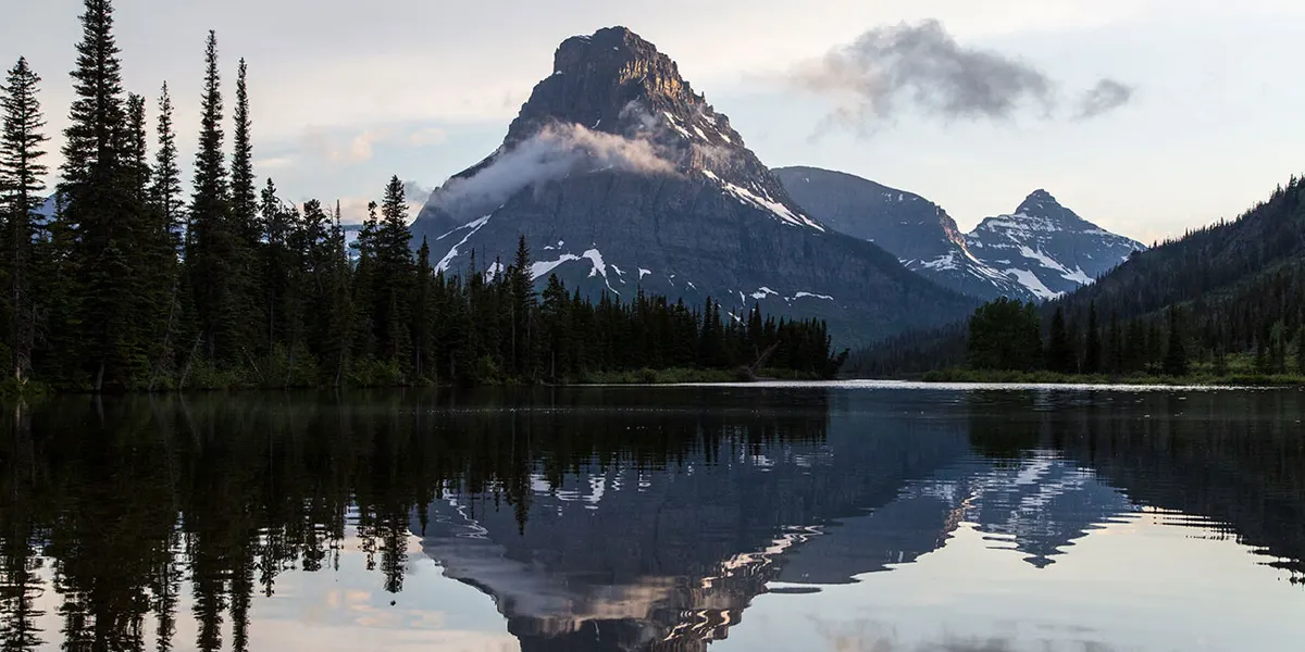 Mountain reflected in calm water near a Glacier National Park campground area