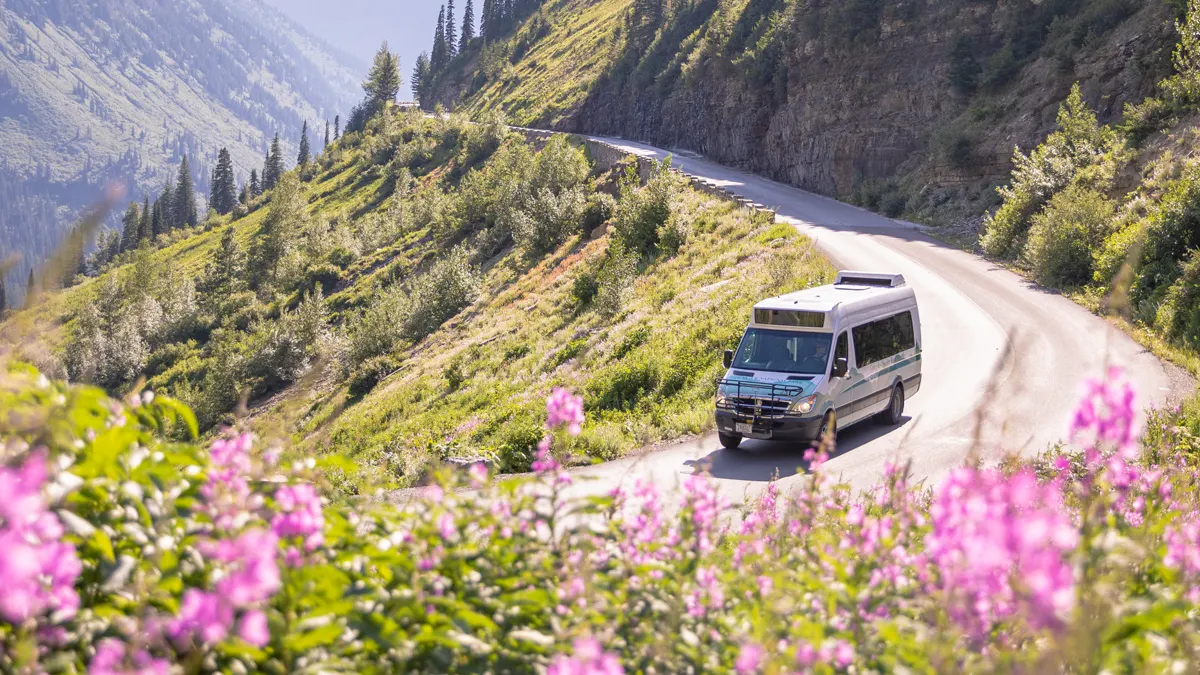 Glacier National Park shuttle climbing a mountain road through wildflowers
