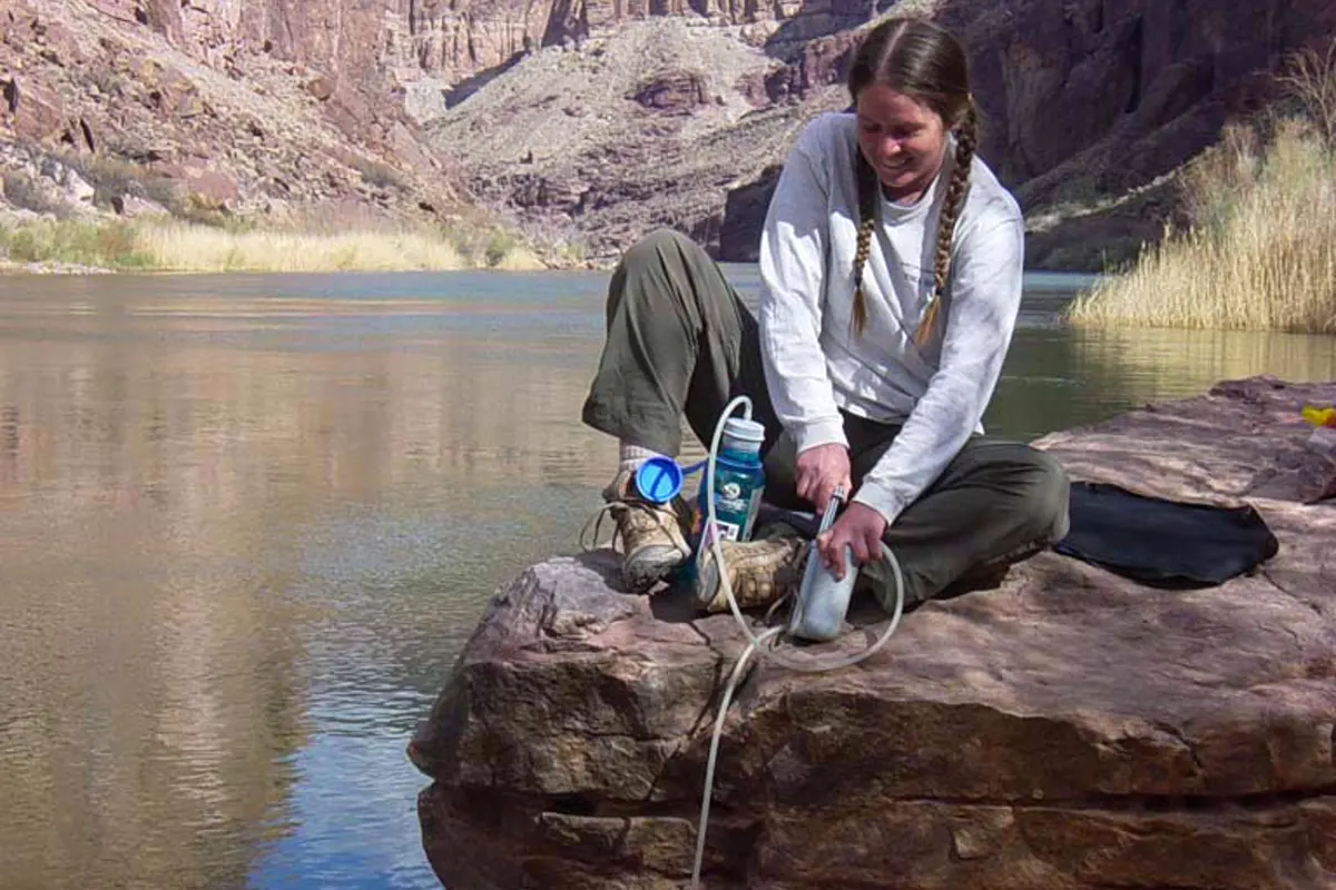 Hiker filtering water above a river in Grand Canyon National Park