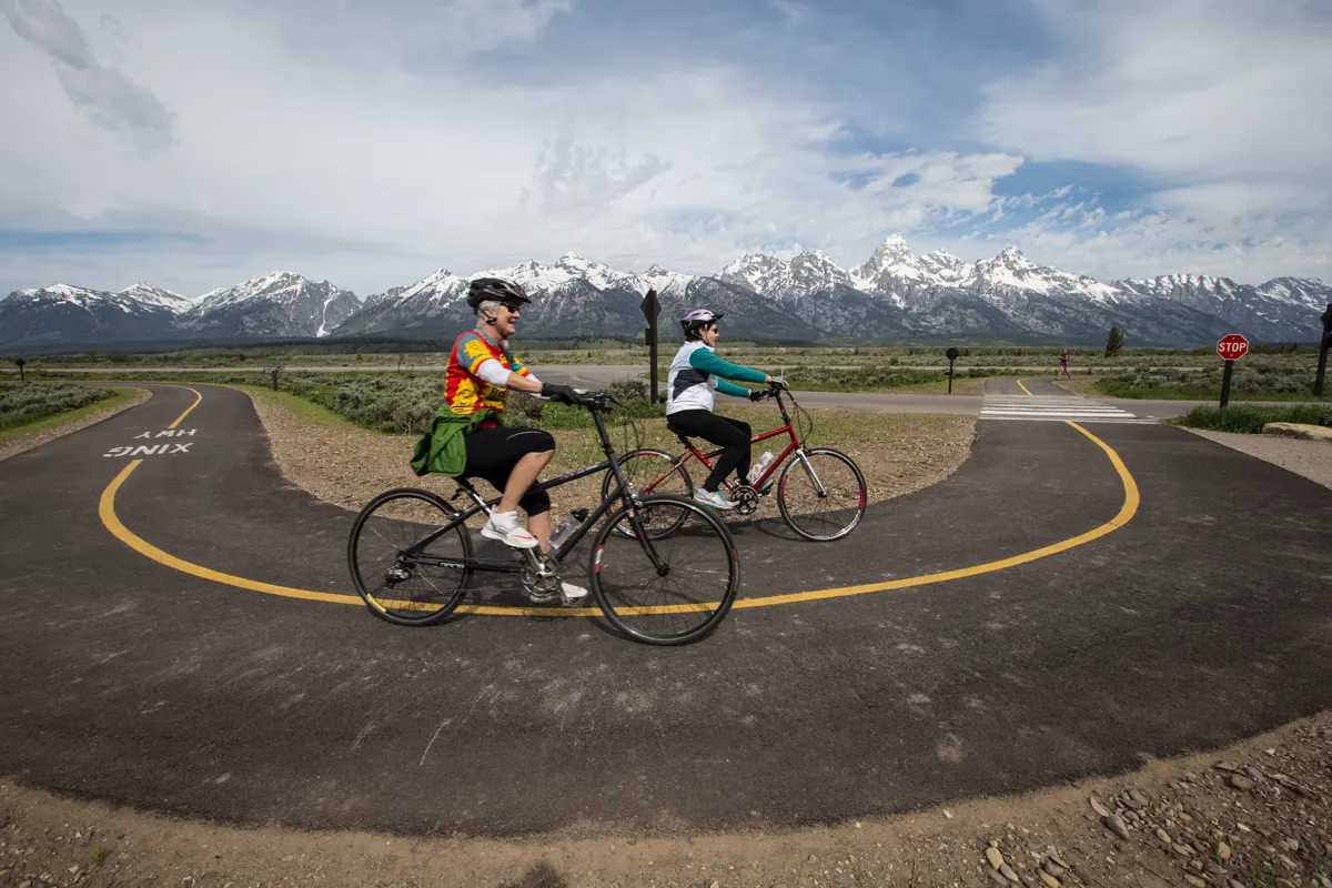 Cyclists following a paved mountain road in Grand Teton National Park