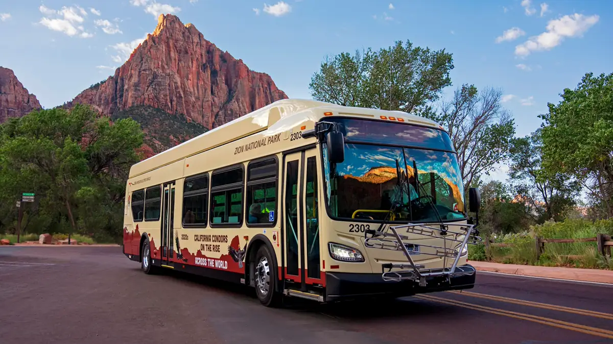 Zion Canyon shuttle bus on the scenic road below sandstone cliffs - Zion National Park | KnowOutdoor