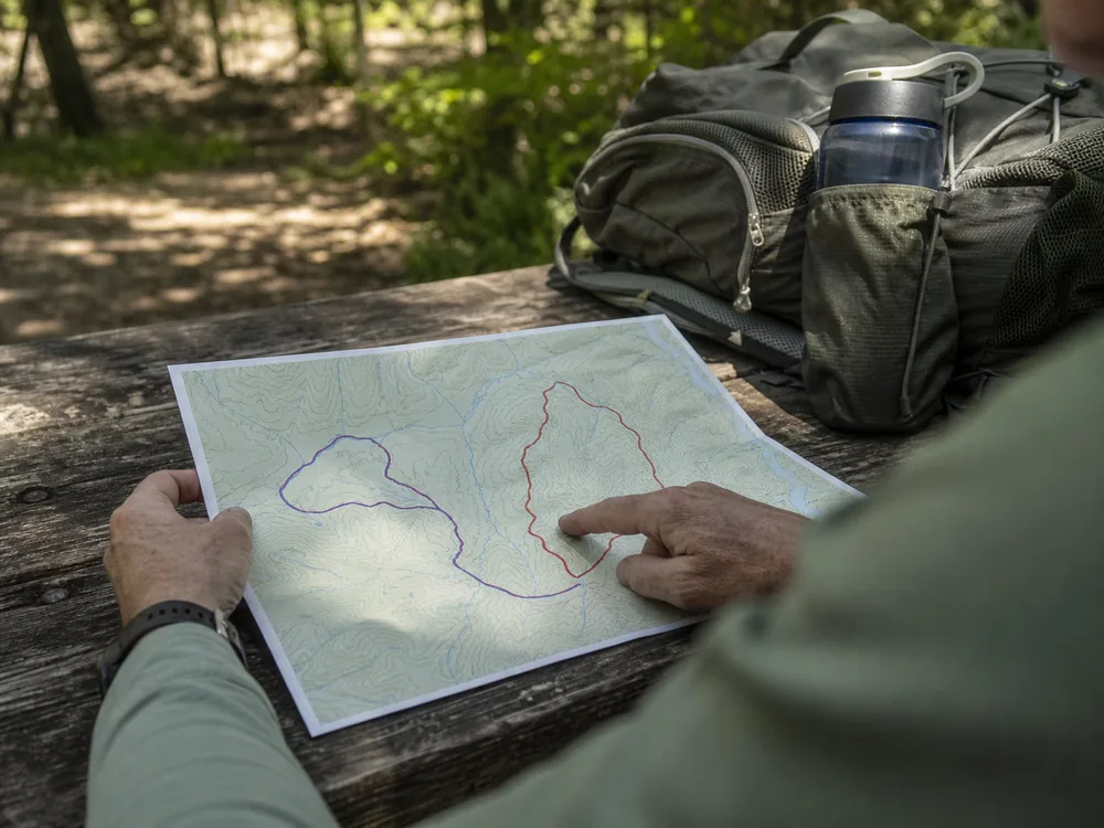 Hiker comparing short out-and-back and loop trail options on a map