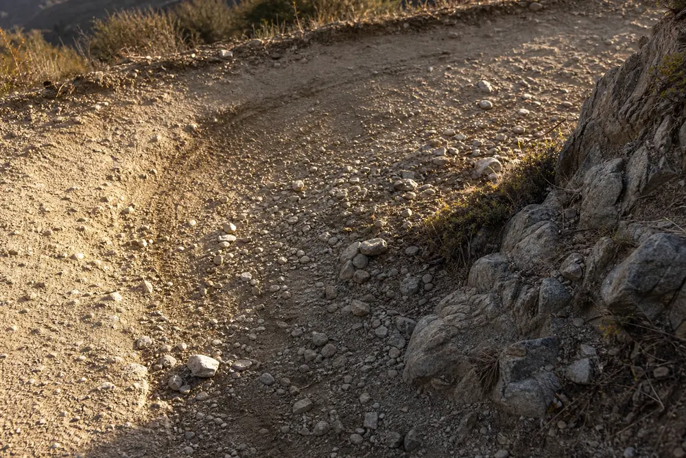 Scuffed skid marks and loose gravel across a switchback corner apex where hikers braked too late - descending switchbacks | KnowOutdoor