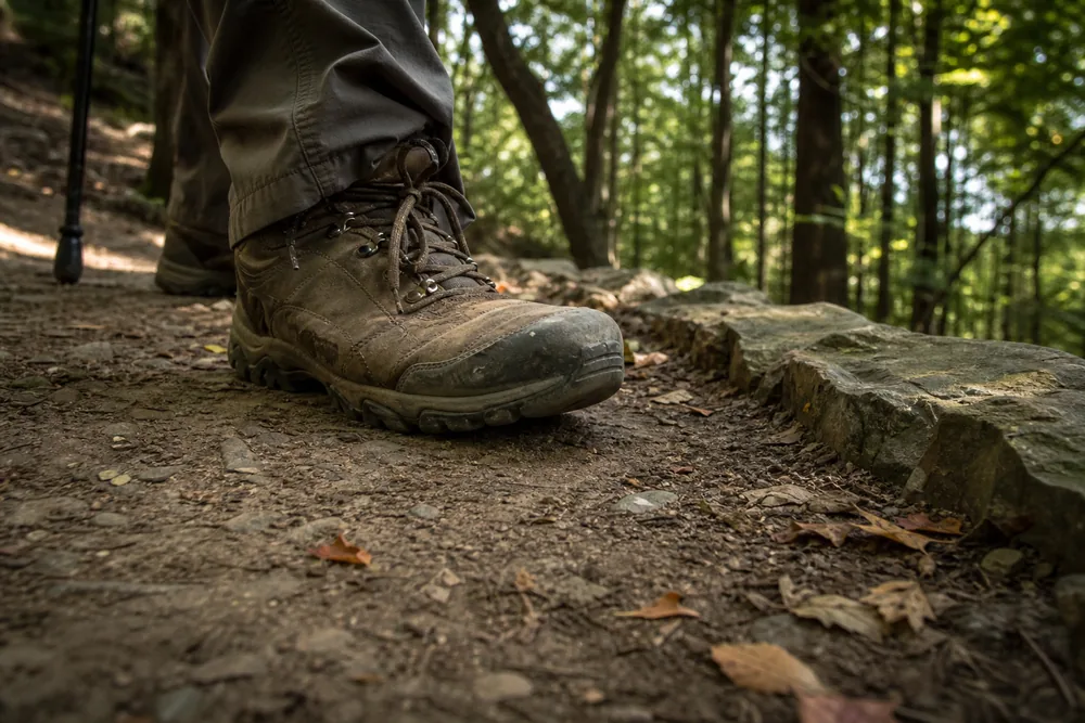 Worn hiking boot planted flat on the wide outer edge of a switchback corner with full lug contact - descending switchbacks | KnowOutdoor