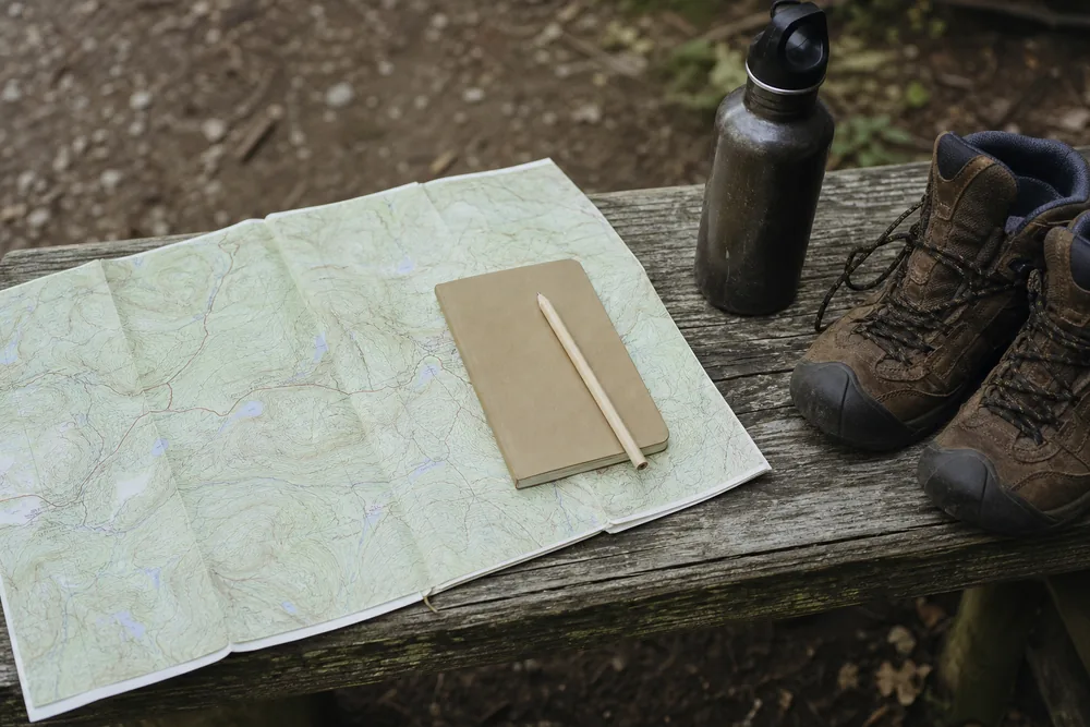 Trail map and notebook used to plan a gradual hiking fitness progression