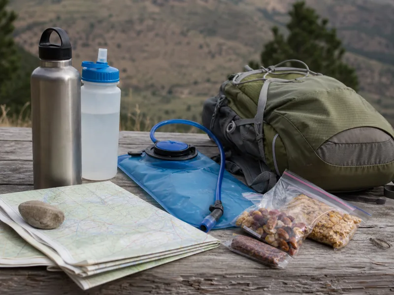 Water bottles, map, and daypack arranged for a hiking water plan
