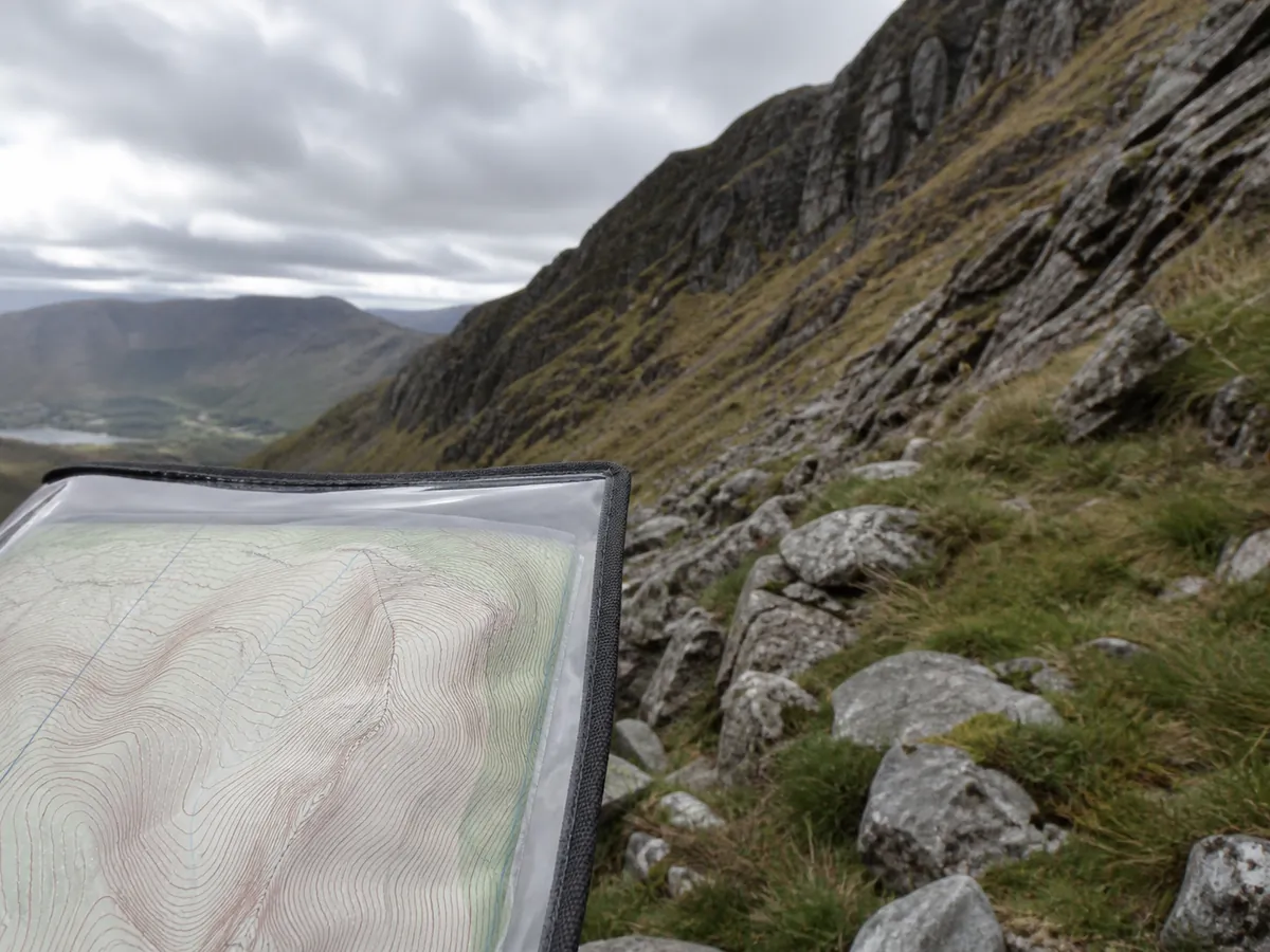 Tightly spaced contours in a map case held below a steep rocky hillside - contour steepness | KnowOutdoor
