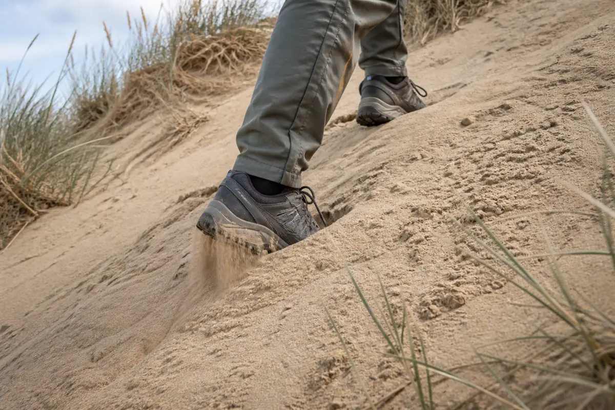 Hiker's boots climbing a steep generic natural dune through loose sand