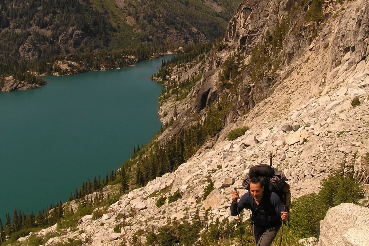 Hiker climbing through steep loose rock on Aasgard Pass
