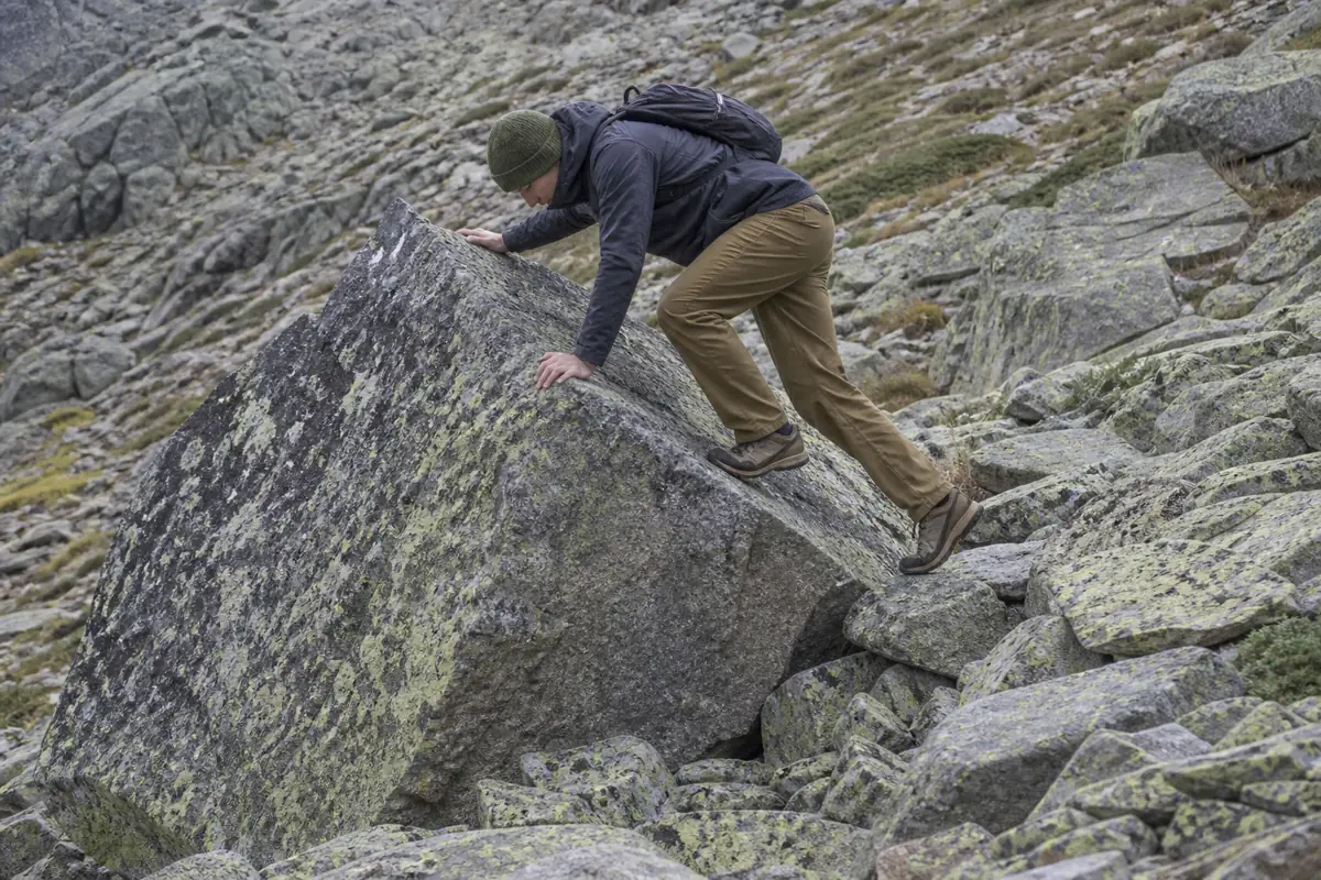 Generic mountain hiker using three points of contact on a waist-high angular boulder