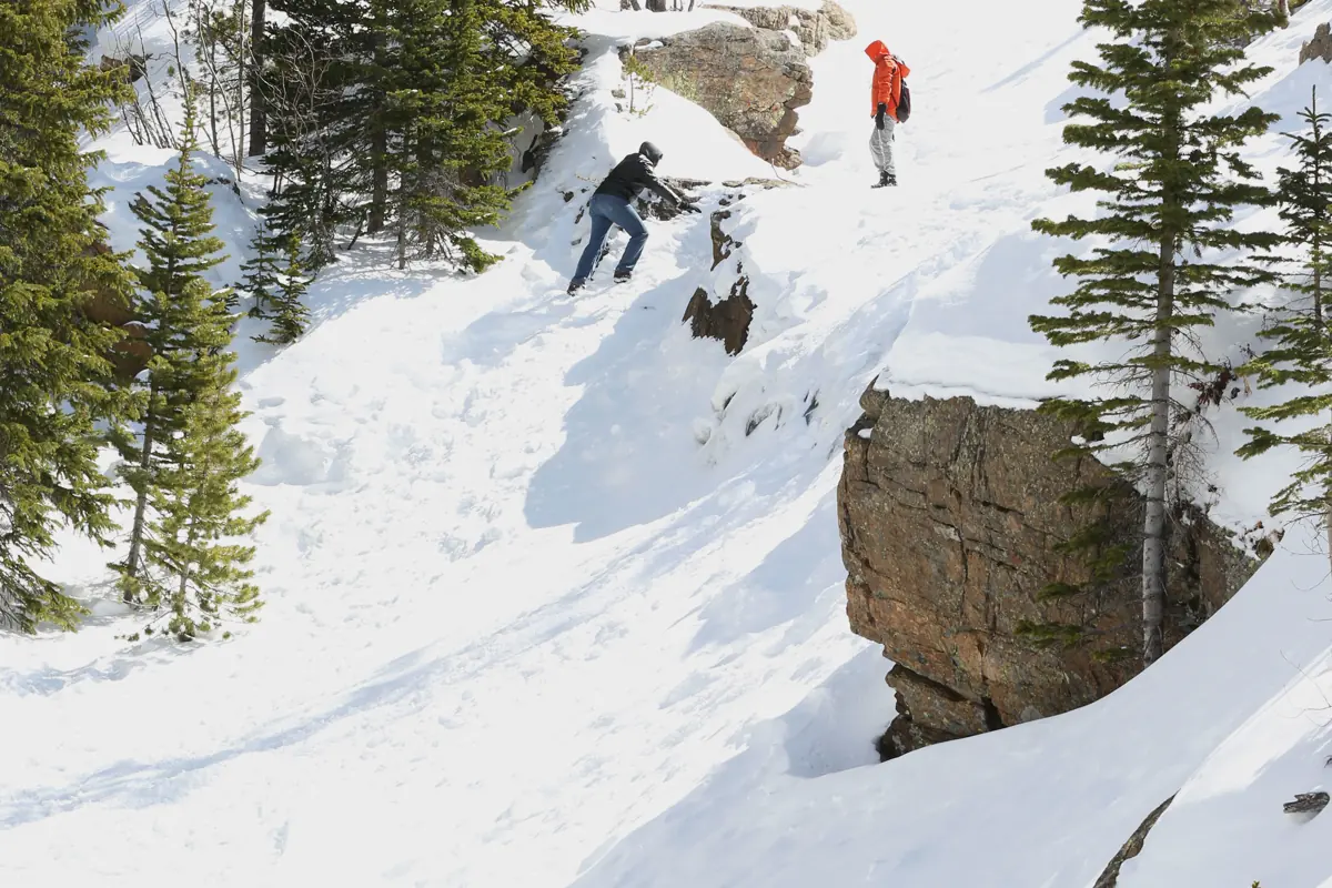 Visitors moving beside snow-covered Alberta Falls in winter conditions