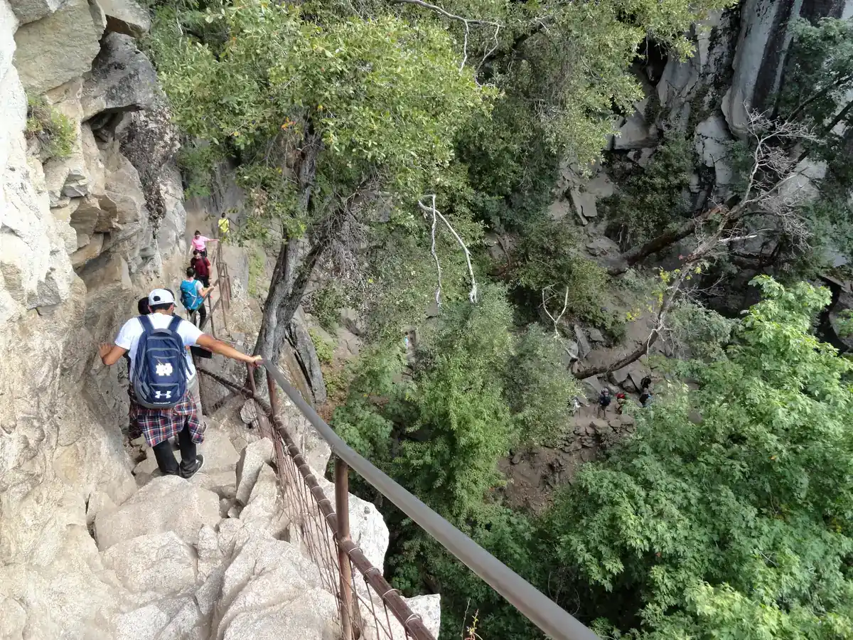 Hikers descending narrow granite steps beside a handrail on Yosemite's Mist Trail - Mist Trail | KnowOutdoor