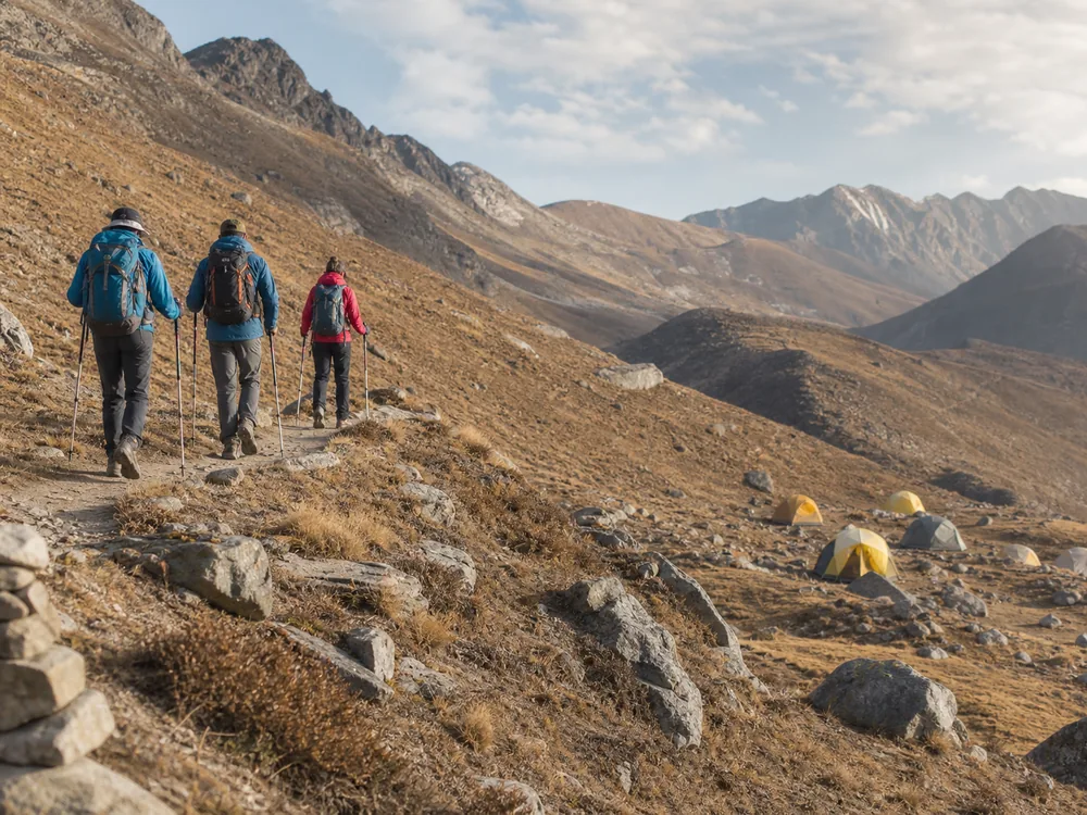 Small trekking group making an easy acclimatization walk above a lower generic mountain camp in clear weather - climb high sleep low | KnowOutdoor