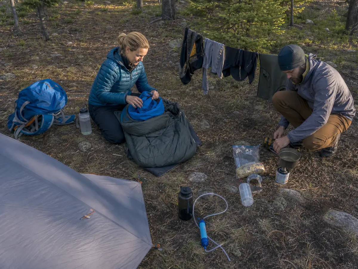 Trekkers separating dry sleep gear, water treatment, food, and wet clothing during an orderly camp setup