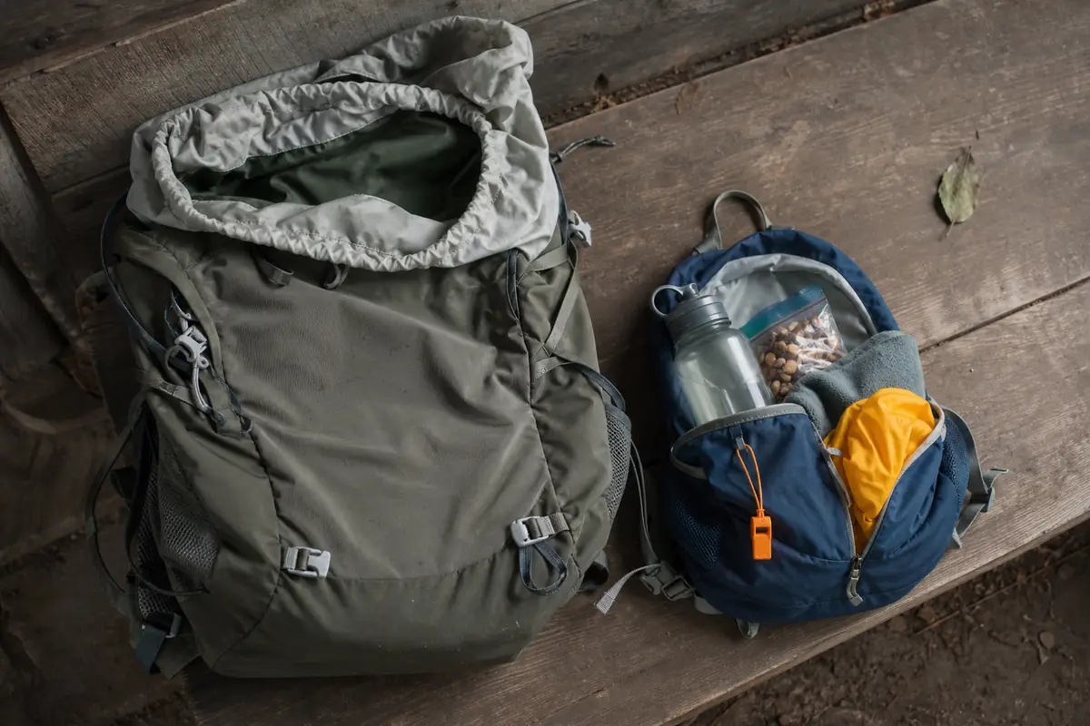 Adult trekking pack with spare space beside a small child pack, layers, water, whistle, and snacks - family pack reserve | KnowOutdoor